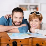 21109949 - portrait of happy couple with map leaning on suitcase in house